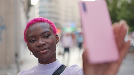 young woman with pink hair takes selfies in the city