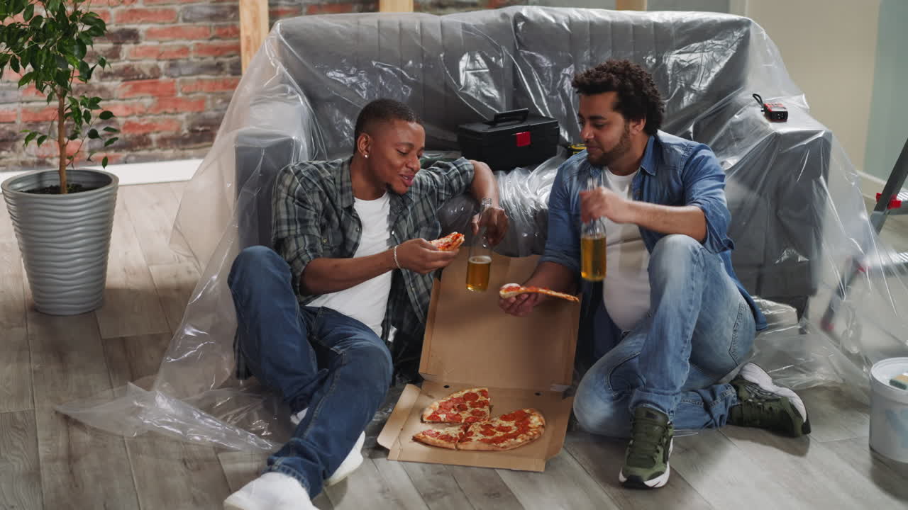African-American brothers with beer bottles eat fresh pizza