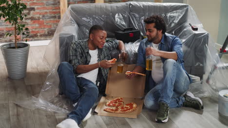 hermanos afroamericanos con botellas de cerveza comen pizza fresca