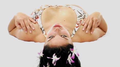 una mujer con bikini y flores en el pelo se acuesta de espaldas y mira a la cámara 1
