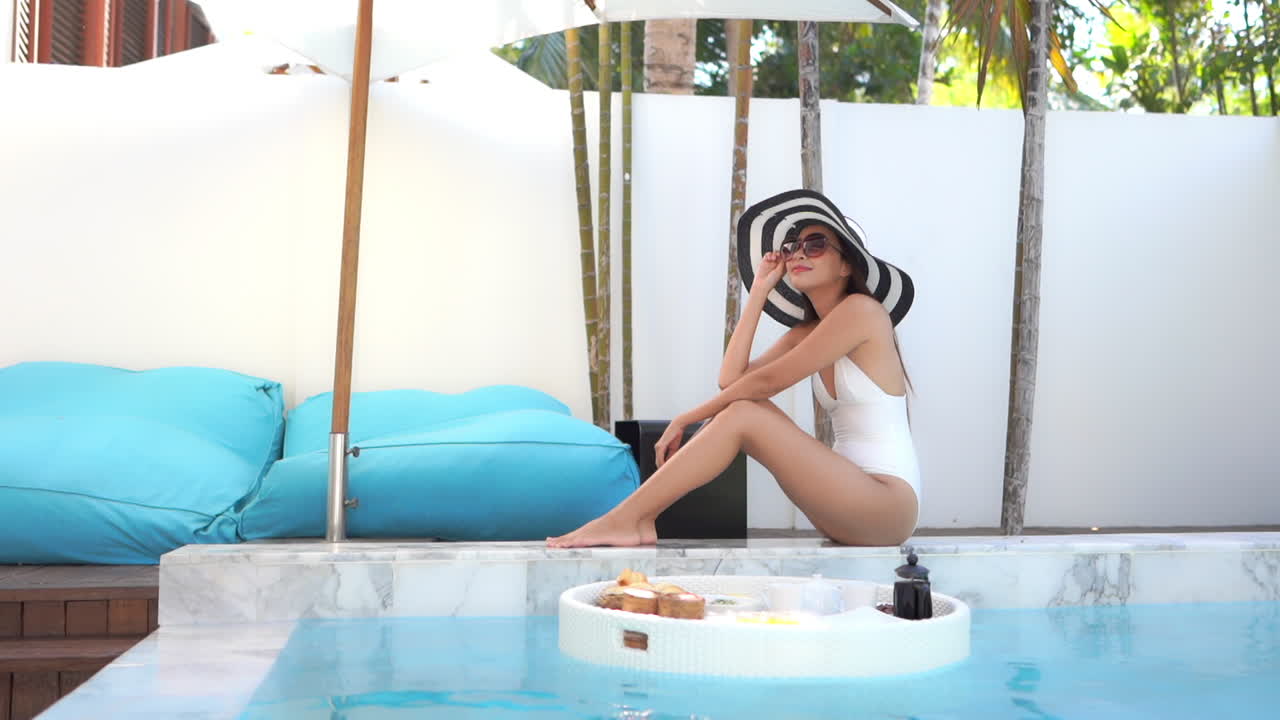 Slow motion of attractive petite asian female by the pool with floating breakfast plate in the water