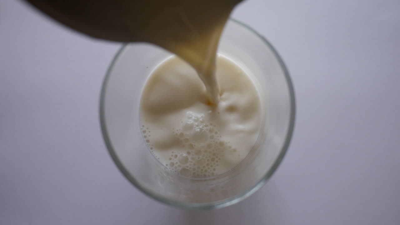 leche entera vertida en un vaso para beber