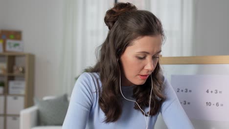 Teacher-in-Earphones-Having-Online-Class-at-Home.distant-education,-primary-school-and-teaching-concept--female-math-teacher-in-earphones-having-online-mathematics-class-at-home