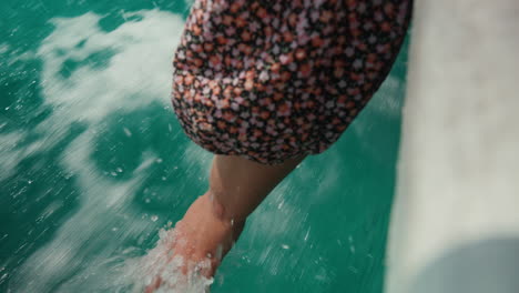 Hand-dipping-into-turquoise-ocean-water-from-boat