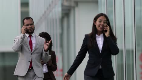 consultores de negocios alegres hablando en teléfonos inteligentes