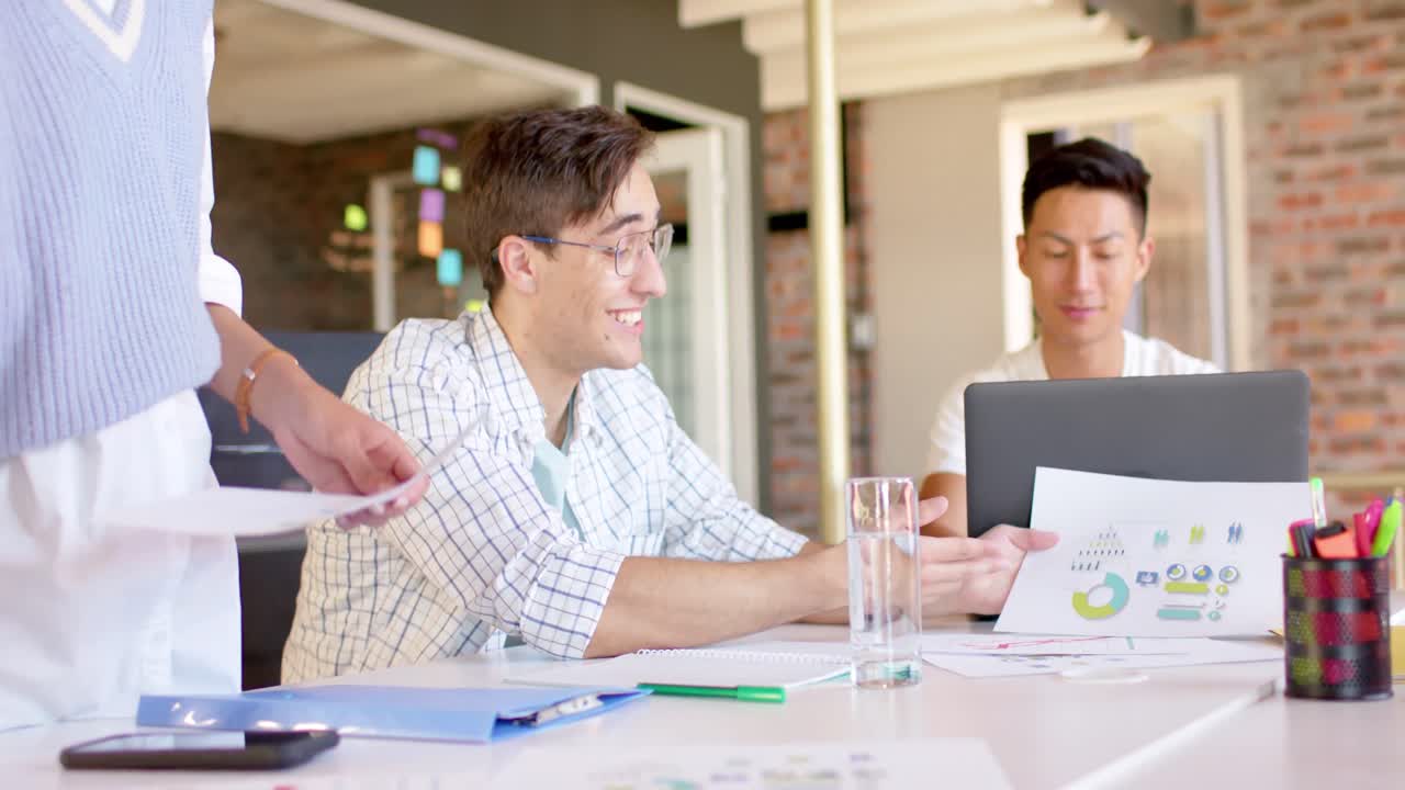 다양한 행복하고 창의적인 남성 동료들이 문서에 대해 느린 속도로 토론하고 있습니다.