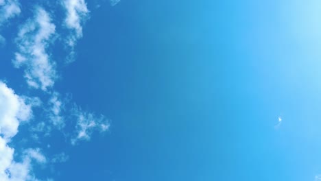 Sky-time-lapse-clouds-and-blue-sunny-sky,-Loop-of-white-clouds-over-blue-sky-with-sun-Rays,-Aerial-view,-drone-shooting-clouds-motion-time,-nature-blue-sky-a-white-clear-weather