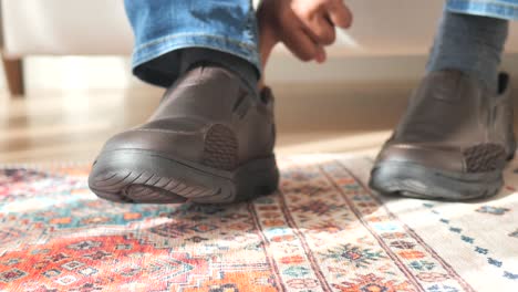 hombre sentado en la alfombra con zapatos de cuero marrón