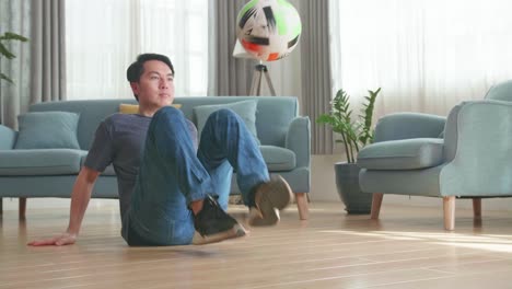 asian man sitting and show skill with soccer ball in living room, soccer freestyle