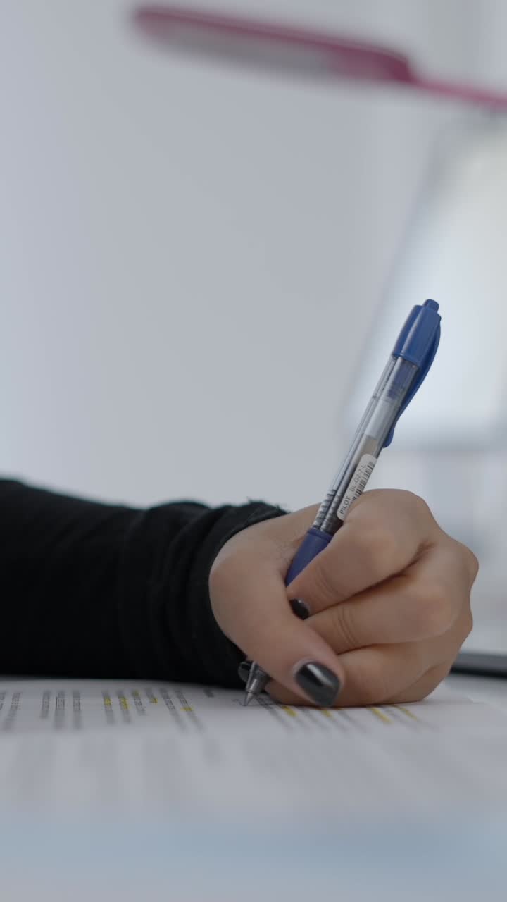 Close-up of a hand writing on a document with a pen