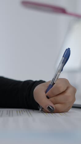 close-up of a hand writing on a document with a pen