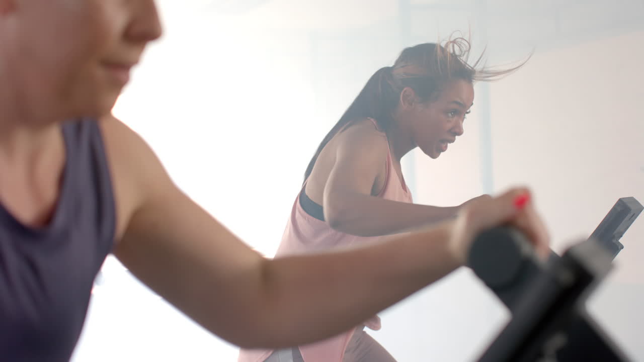 체육관에서 슬로우 모션으로 타원형 자전거를 타고 훈련하는 다양한 여성
