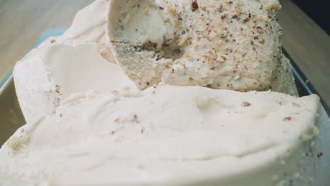 a close-up of a creamy hazelnut ice cream infused with eucalyptus being scooped out using a metal scoop. it has a smooth texture, herbal aroma, and an artisanal look.