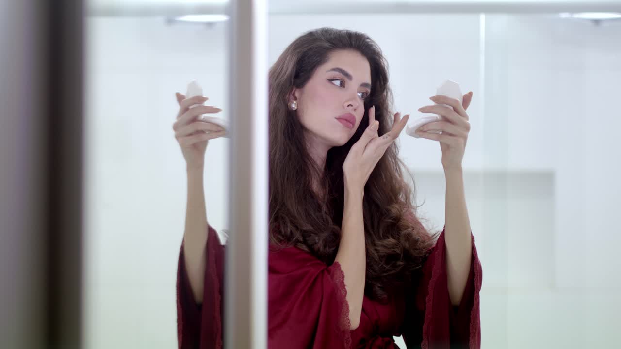 la hermosa morena aplica cuidadosamente y pacientemente un maquillaje caro