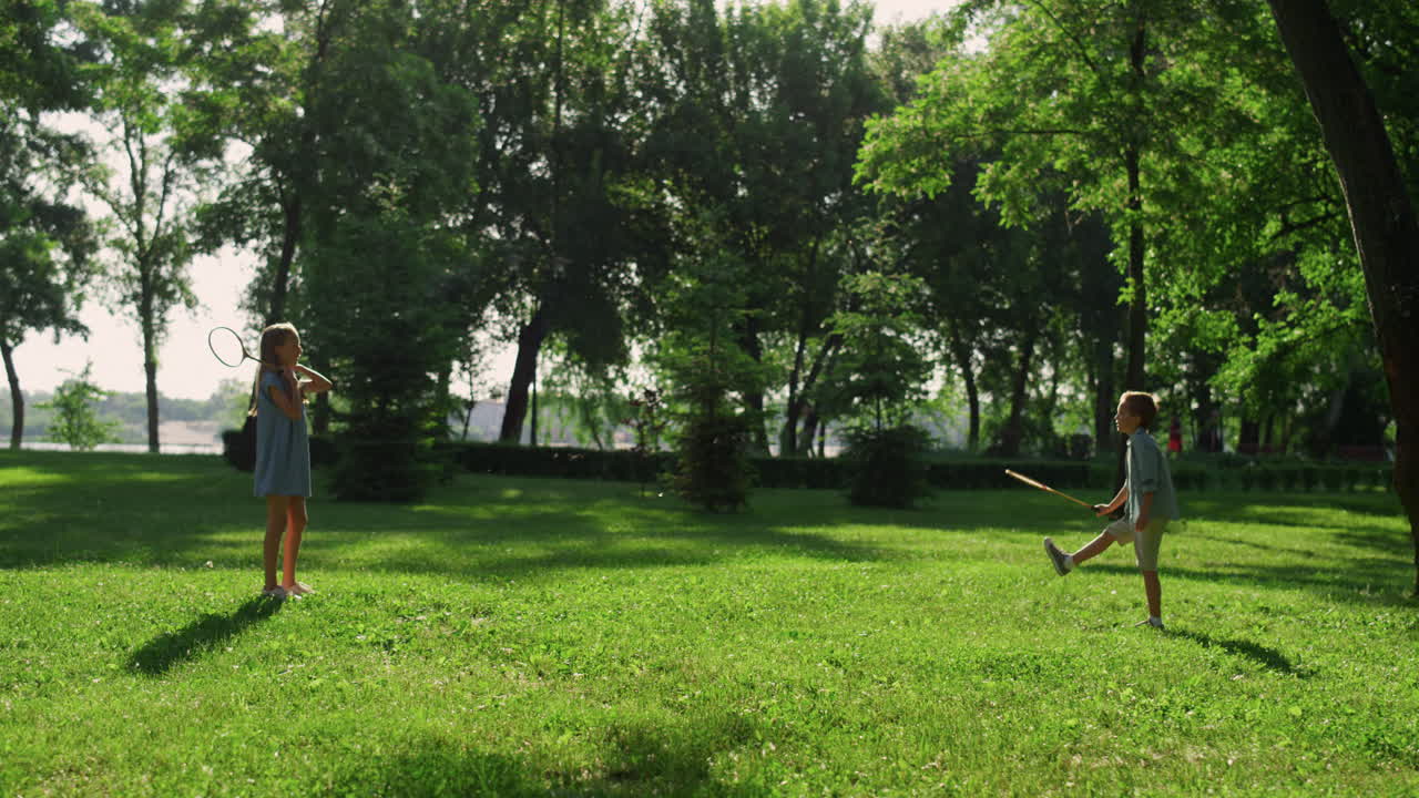 una pareja de hermanos juegan raquetas de bádminton charlando en el parque verde. picnic de verano