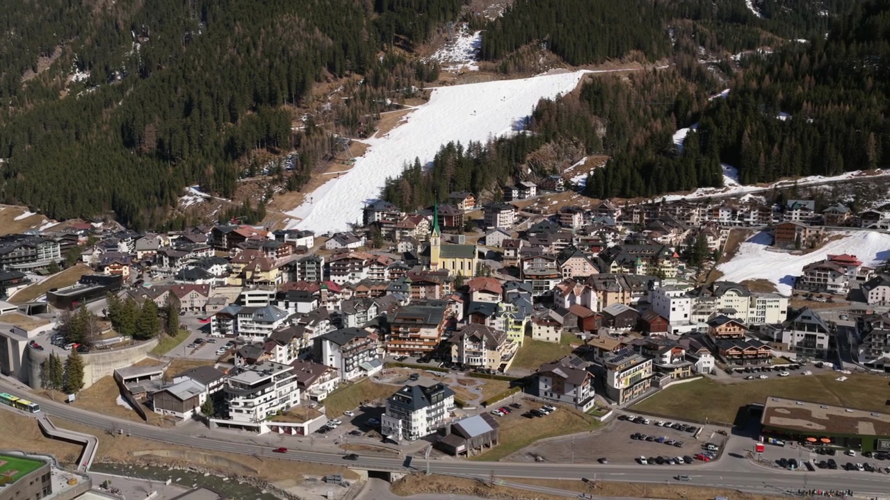 Kirke med grønt spir og traditionelle hoteller i skisportsbyen Ischgl i Paznaun-dalen i Tyrol, Østrig. Kredsende luftfoto.