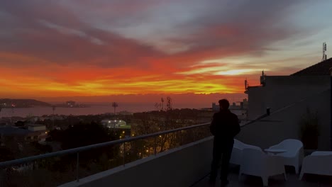 young man admire and enjoying beautiful sunset over city and tagus river at luxury bar