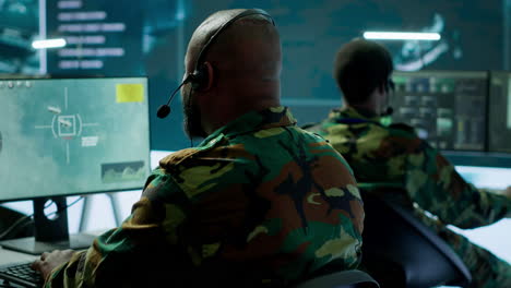 personal militar en la base de operaciones utilizando computadoras avanzadas y pantallas grandes