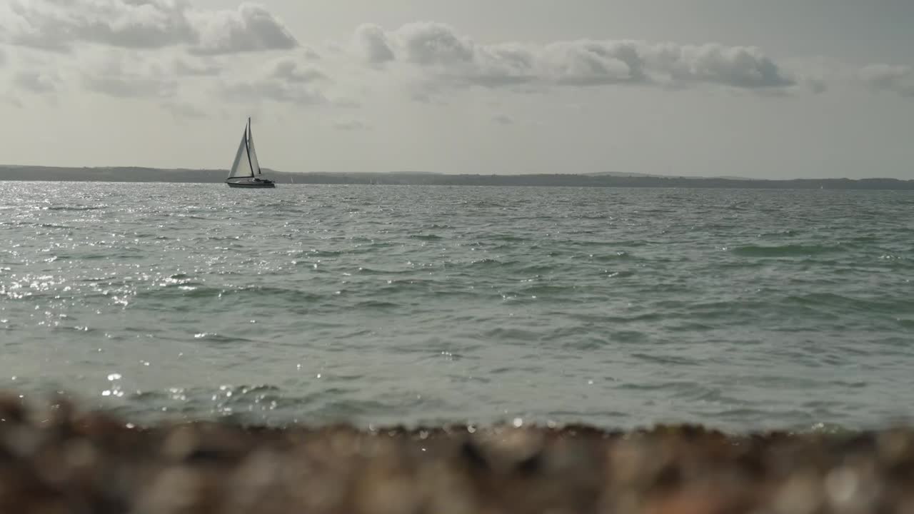 배 가 바다 에 떠다니고, 물결 이 앞면 에 있는 자갈 들 에 부 ⁇ 히고 있다