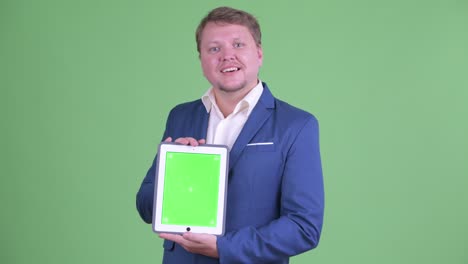 retrato de un hombre de negocios caucásico mostrando una tableta digital con espacio de copia disparada contra un fondo verde
