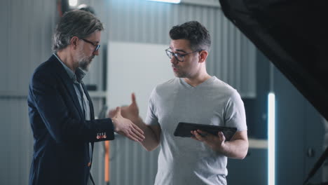 two men discussing car repair and diagnostics in an automotive garage