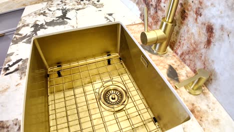 gold kitchen sink with brass faucet and marble countertop