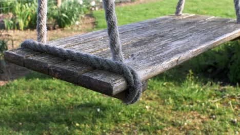 locked off view of wooden swing seat gently swaying in the wind