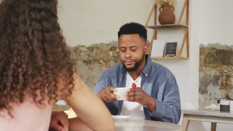 pareja feliz diversa pasando tiempo juntos en una cafetería, bebiendo café y hablando