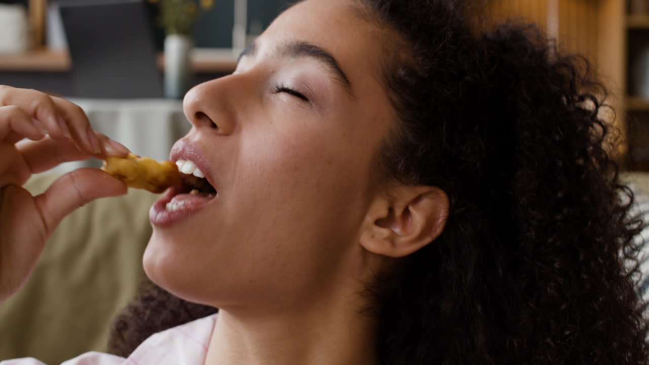 Close-up of a woman savoring a snack with closed eyes