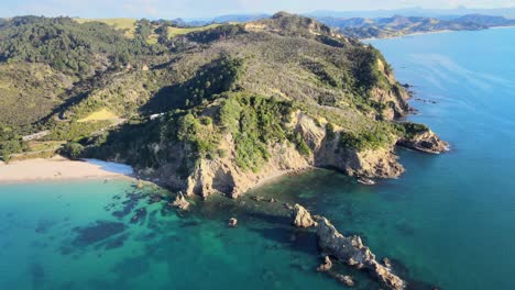 acantilado rocoso con bosque junto a la playa en la costa de la península de coromandel, destino popular para el ocio y la relajación