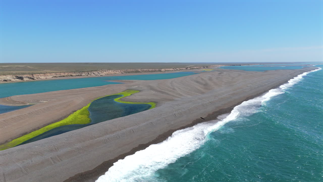 Waves break on sandbar near the sunny, arid shore of the Valdes Peninsula, Argentina