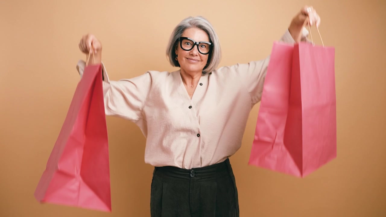 Donna matura felice con borse della spesa su sfondo beige