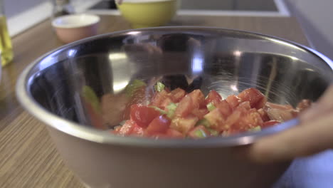 mezclando verduras, tomates y paprika con cebollas en la cocina, preparando una comida, toma de ensalada a cámara lenta