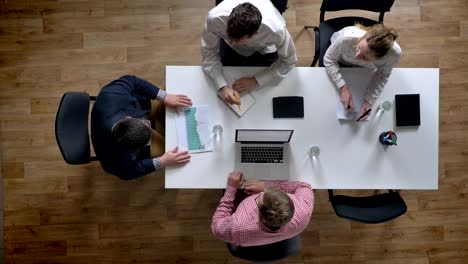 boss coming in and team of four people starting meeting, topshot, businessmen planning new project in modern office