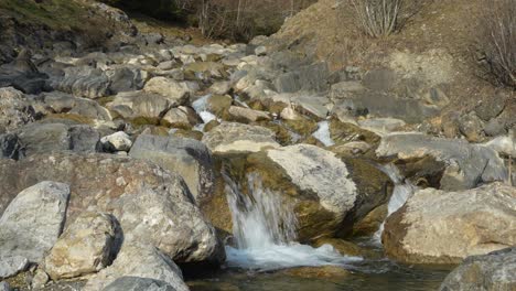 static shot of a small waterfall with crystal-clear water flowing over smooth rocks in a tranquil natural setting.
