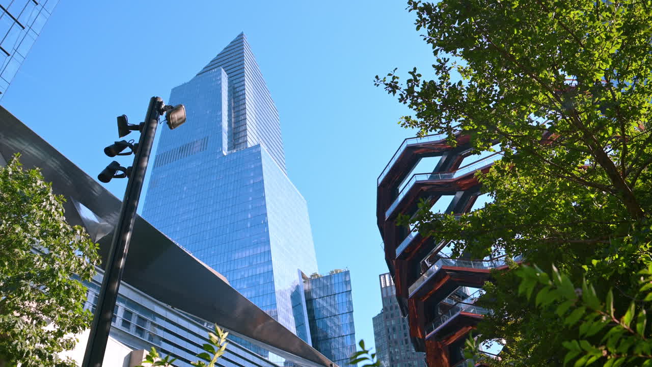 Poste com câmeras de rua, árvores, edifícios altos e a escultura Vessel. Vista de baixo da rua de Nova York, EUA