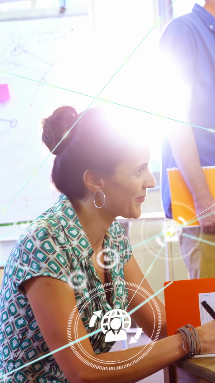 Seated woman turning and speaking in meeting, causing HUD icons linking as man entering for ideas