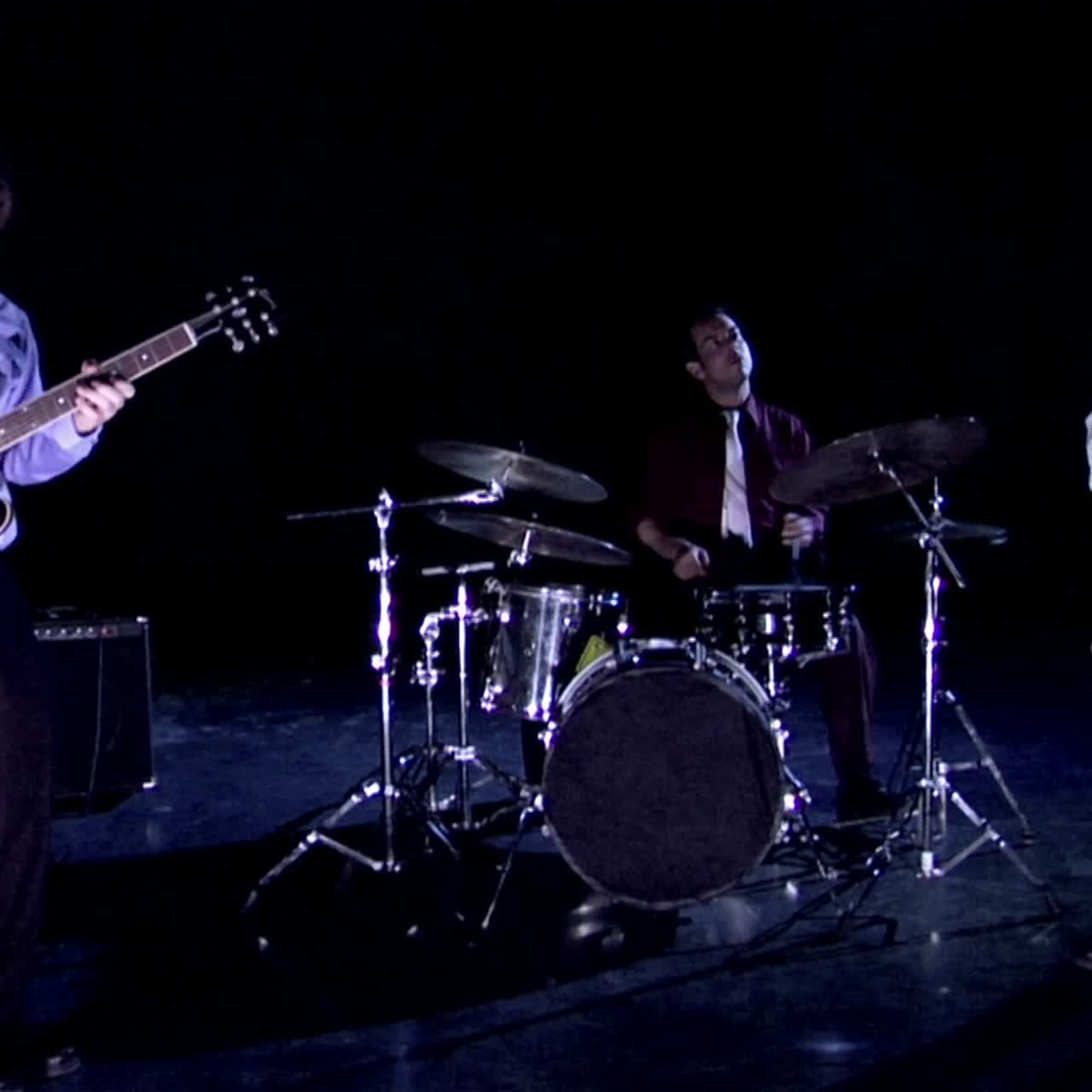 Una band suona su un palco oscurato.