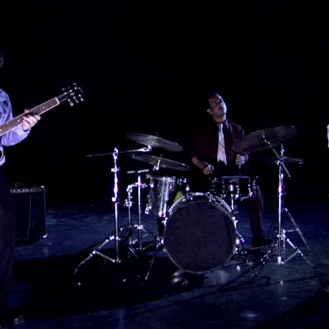 a band plays on a darkened stage