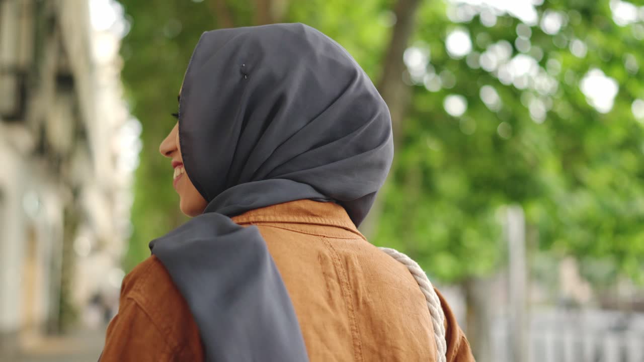 Young Muslim Woman in Hijab Smiling and Walking on a City Street