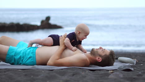 amidst the beach setting, a young father delights in playful bonding with his newborn son. these special moments enhance his vacation experience. he embodies the joy of fatherhood