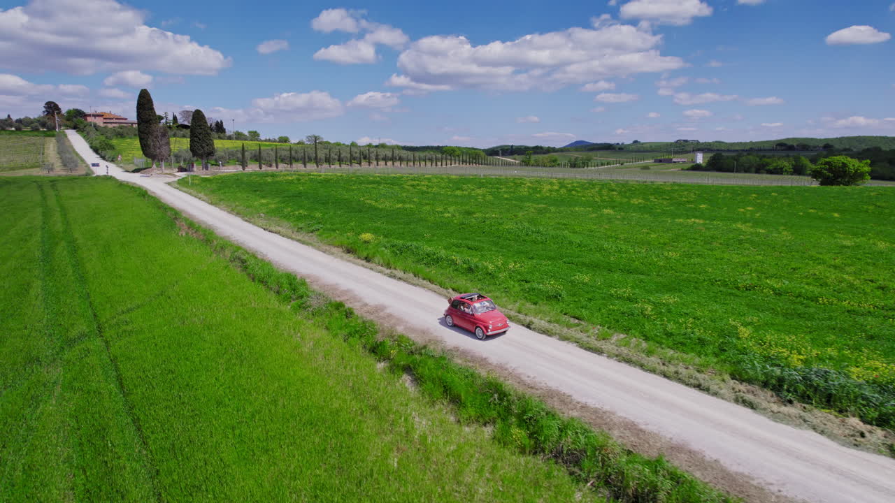 ⁇ 은 초록색 토스카니아 농경지에서 운전하는 빨간 차의 공중 철수