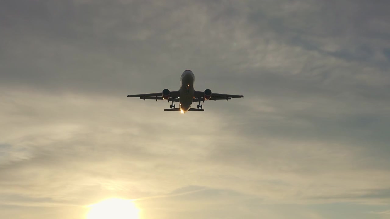 Aereo passeggeri in decollo contro un cielo dorato al tramonto