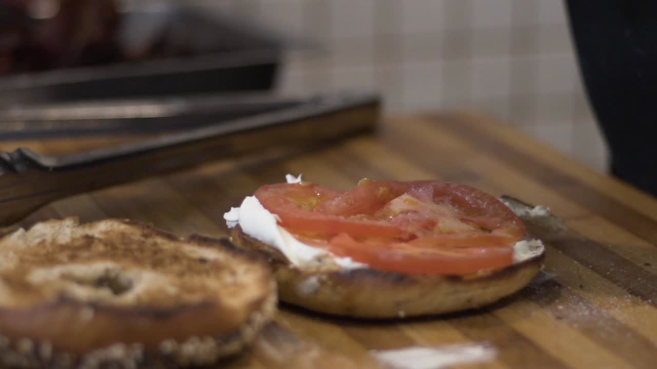 Ripresa ravvicinata al rallentatore di sale gettato su pomodoro su un bagel