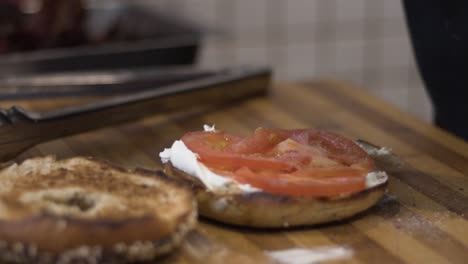 slow motion close up shot of salt being thrown onto tomato on bagel
