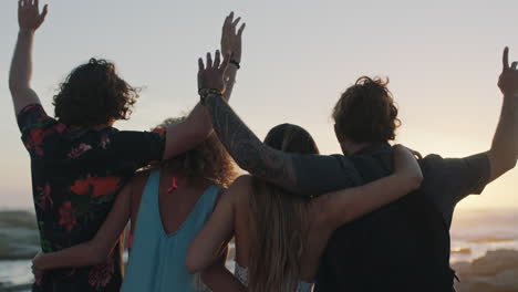 group of friends embracing on beach celebrating with arms raised