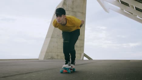 retrato épico y primer plano de un joven y atractivo hombre de moda patinando rápido bajo un panel solar en un día soleado por la mañana con un fondo urbano en cámara lenta