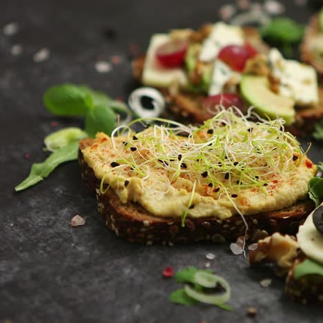 vielzahl gesunder frischer sandwiches mit verschiedenen gemüsekräutern und zutaten auf dunklem tisch