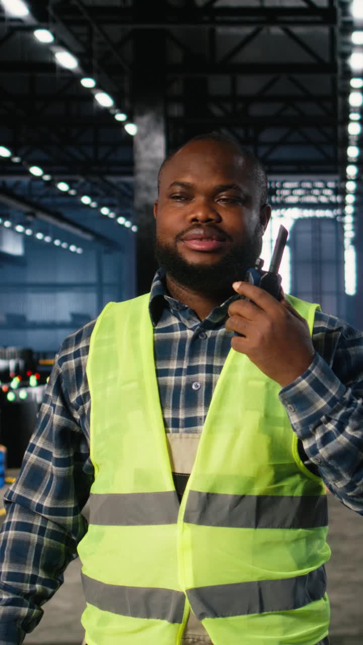 Vertical Video Black manufacturing employee uses walkie talkie to speak with supervisor