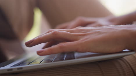 Young-woman-types-letter-on-keyboard-of-modern-laptop